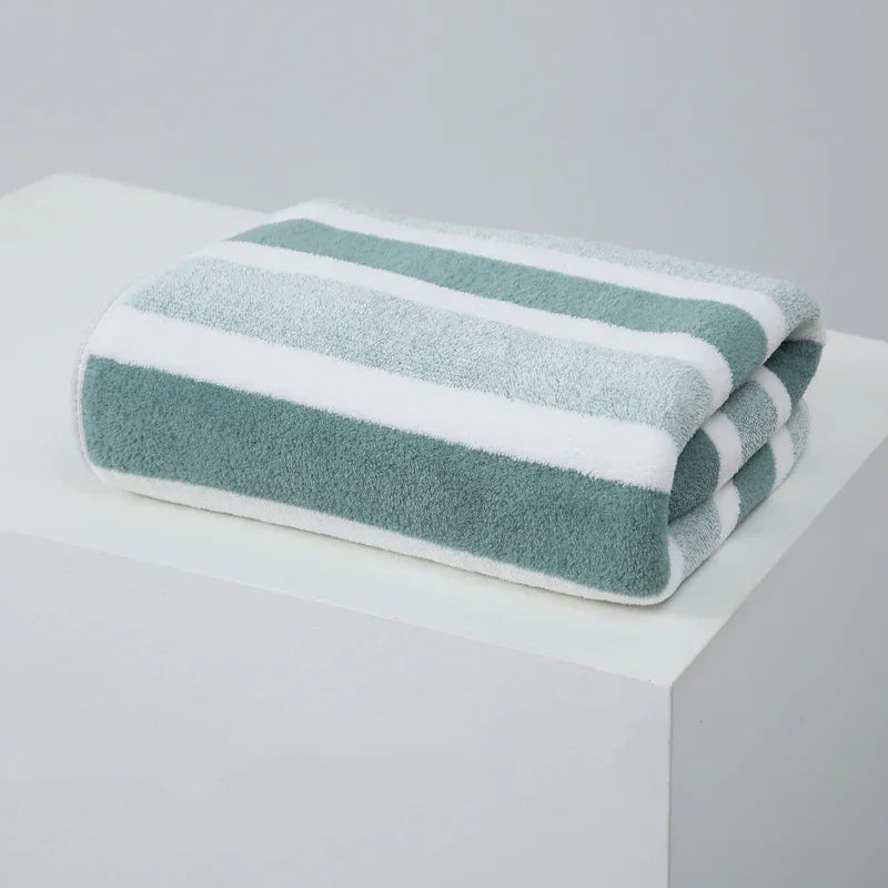 Folded green and white striped towel on a white table, minimalist setting